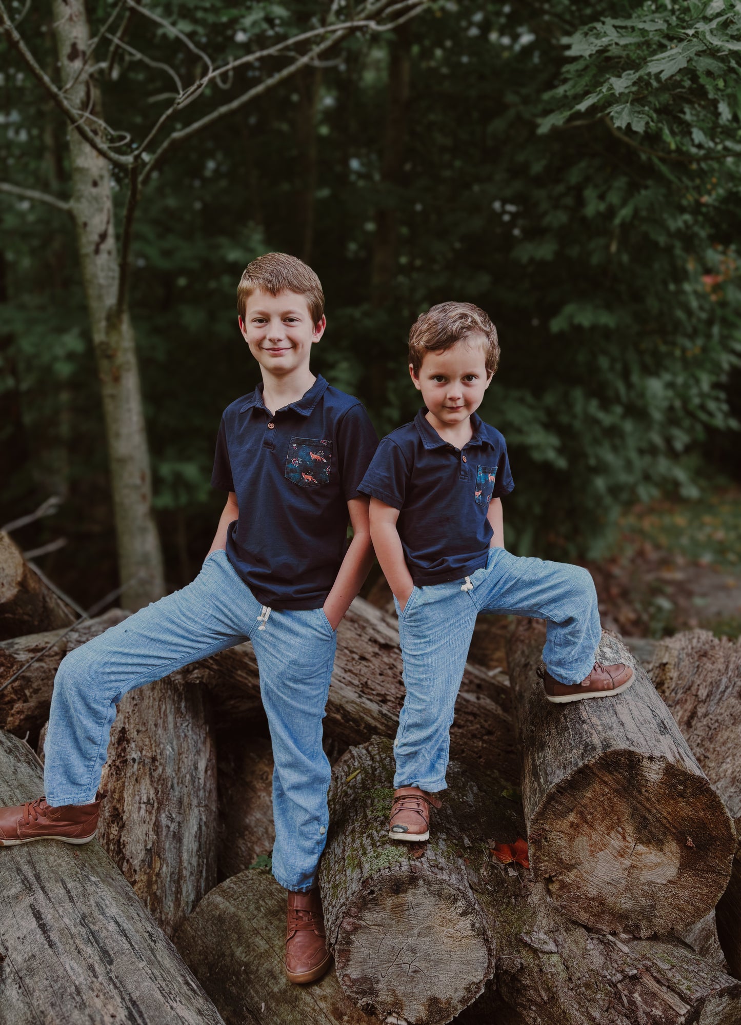 Two boys in matching outfits on logs.