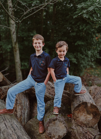 Two boys in matching outfits on logs.