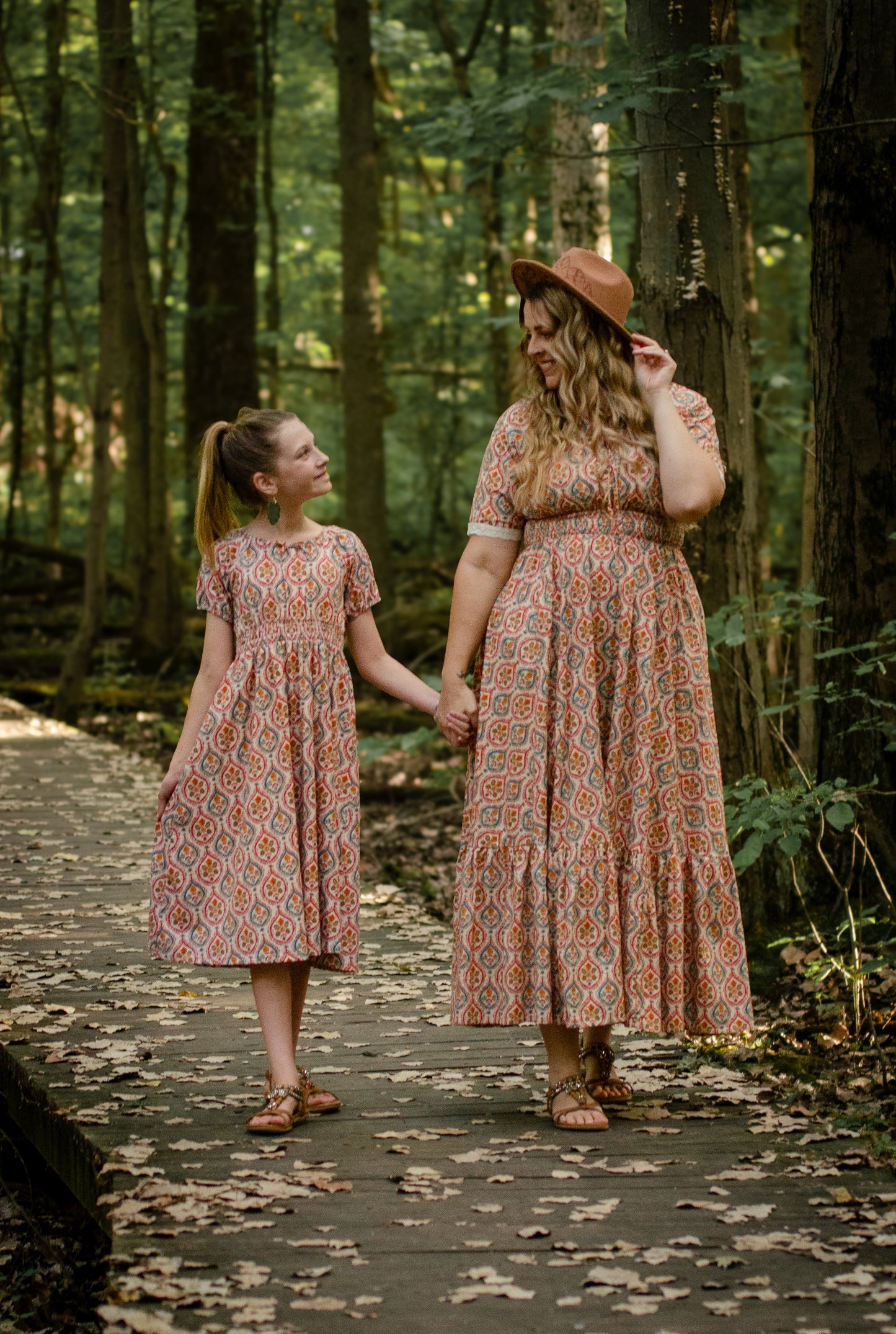 Woman wearing a patterned modest nursing dress with her daughter wearing a matching dress