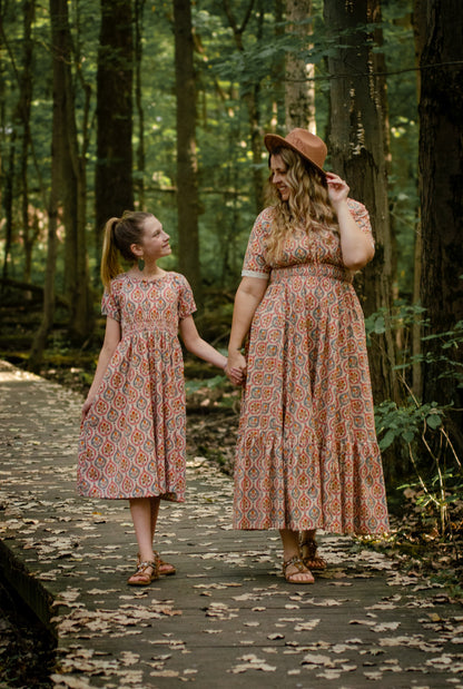 Woman wearing a patterned modest nursing dress with her daughter wearing a matching dress