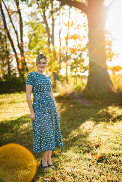 Woman in modest nursing dress, sunlit forest.