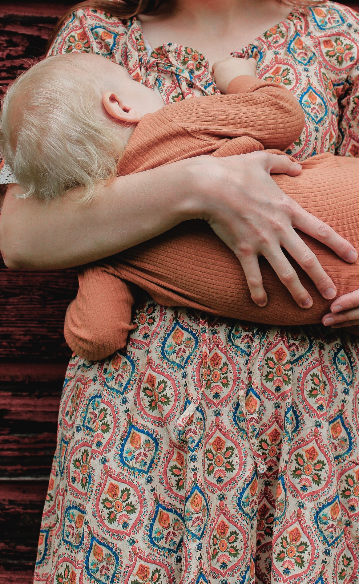 Woman wearing a patterned modest nursing dress with her baby