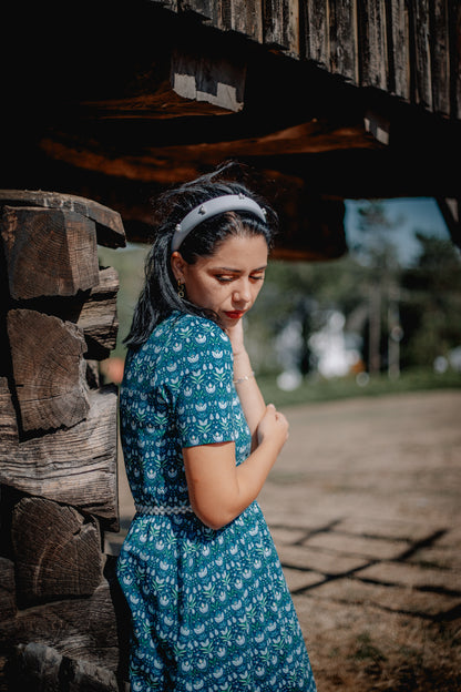 Woman in modest nursing dress, outdoor wooden structure.