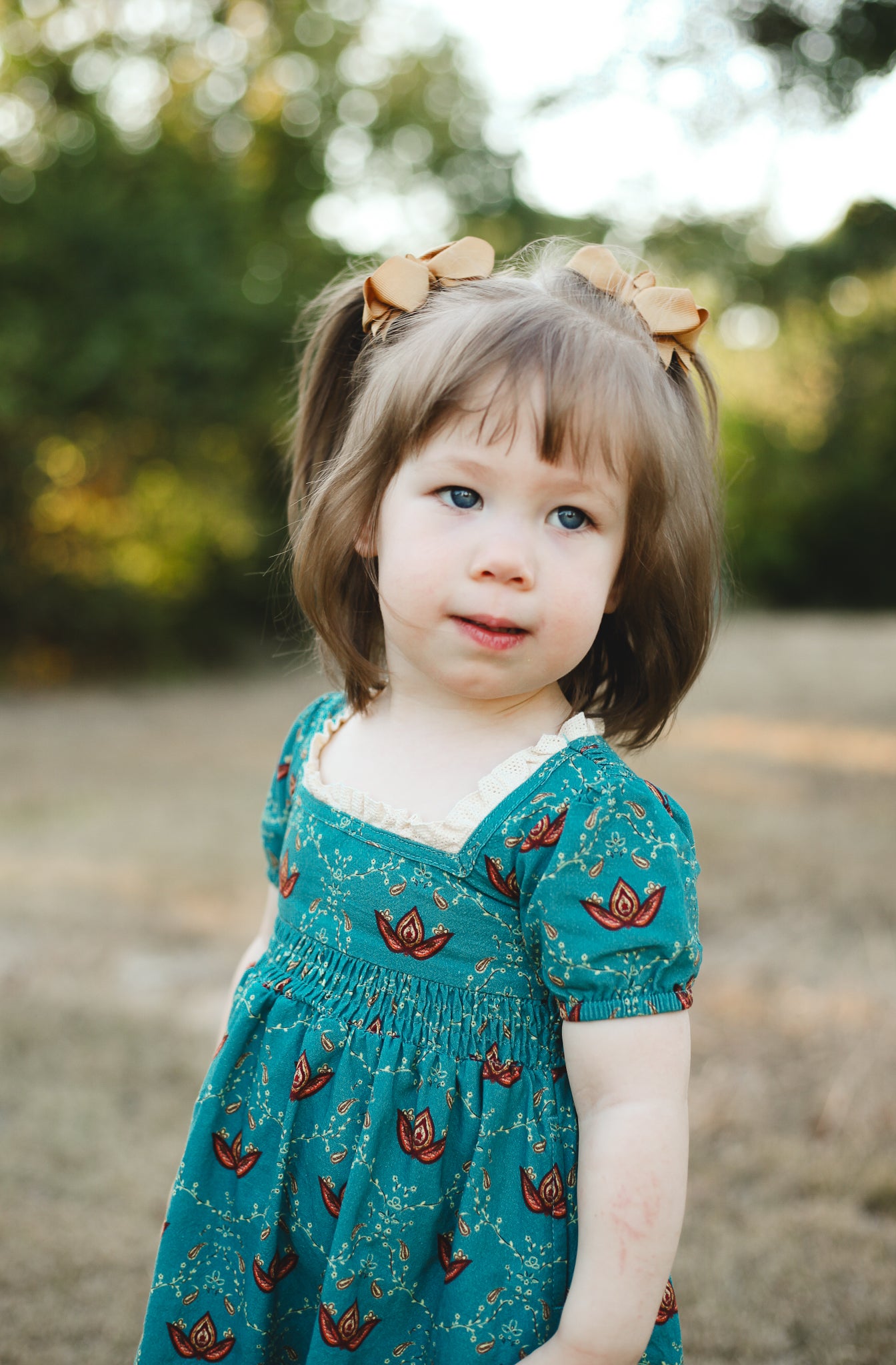 Young girl wearing modest dress with patterns outdoors.