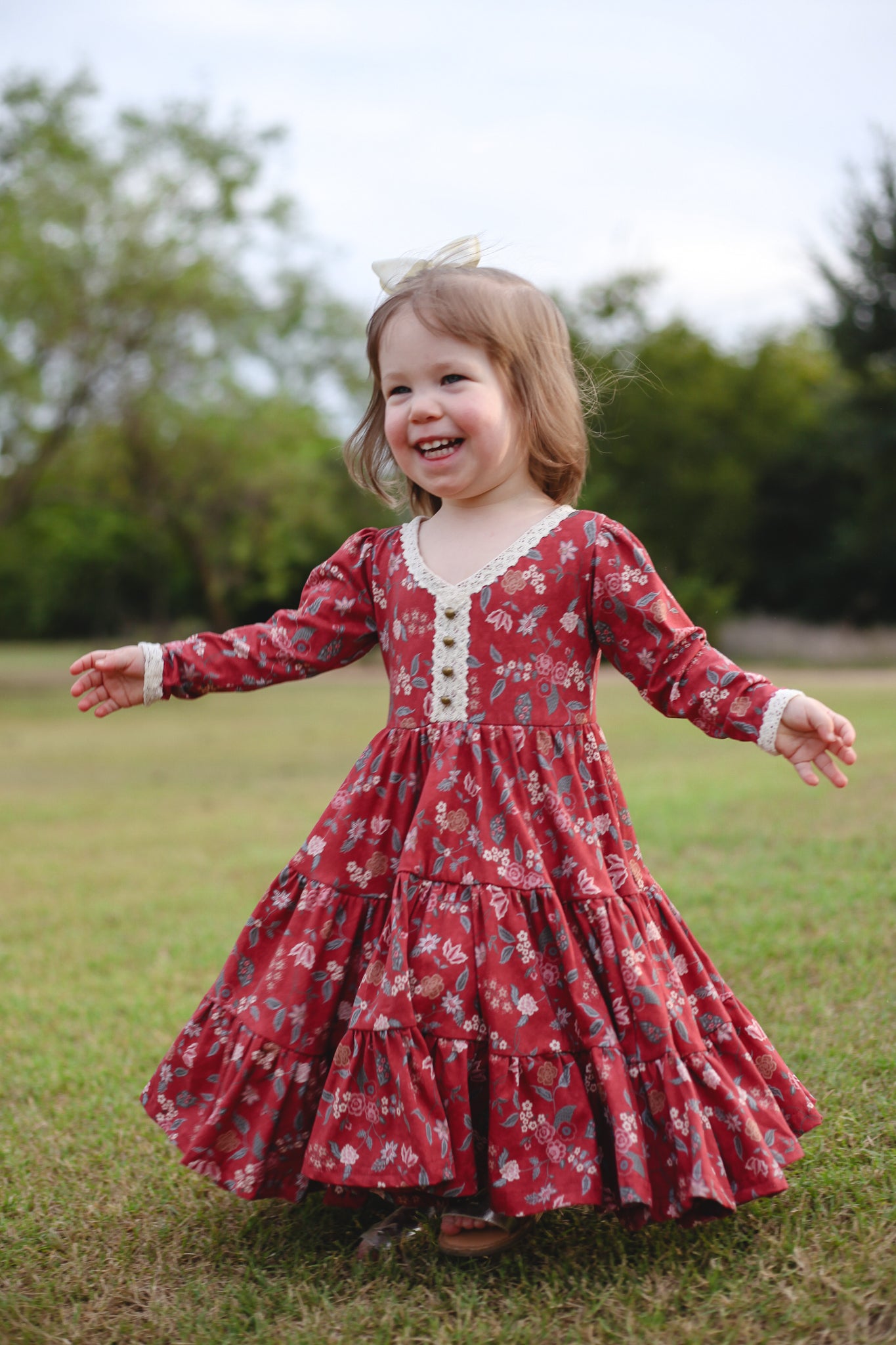 Child in modest red floral dress with arms outstretched