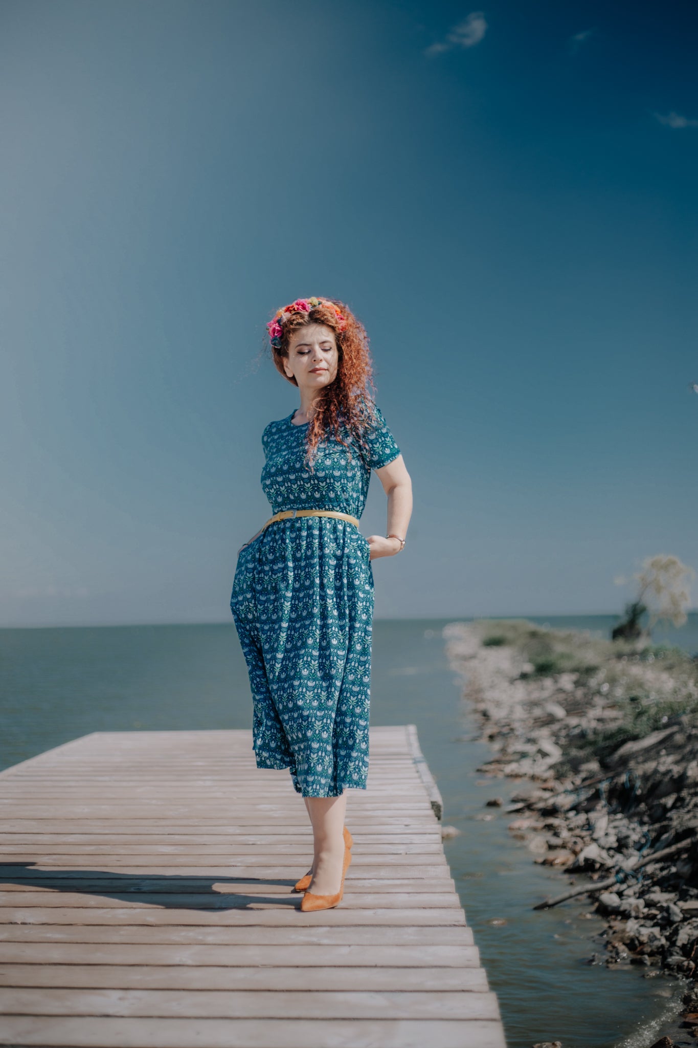 Woman in modest nursing dress, dock by water.